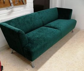 Vihreällä samettikankaalla verhoiltu sohva